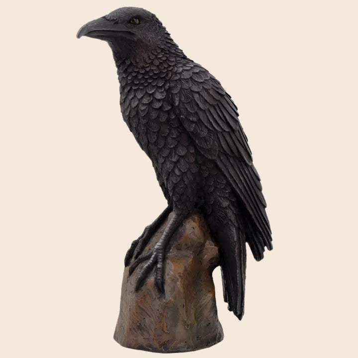 Statue of a crow perched on a branch with a white background