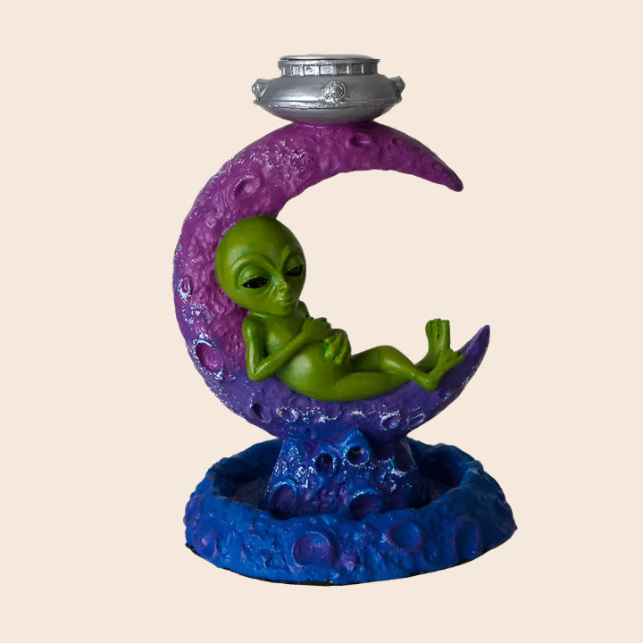 Decorative figurine of an alien on a purple crescent moon with a blue base.