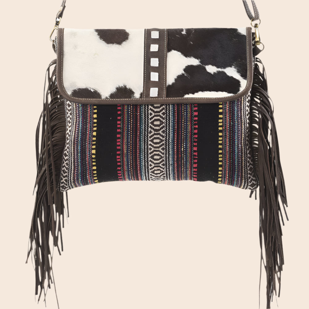 Handbag with cowhide leather and patterned fabric, featuring fringes on a white background