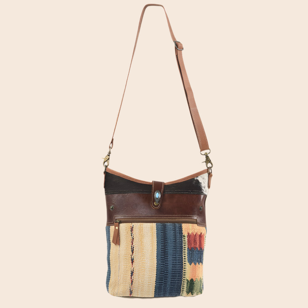 Multicolored patchwork handbag with brown leather accents on a white background