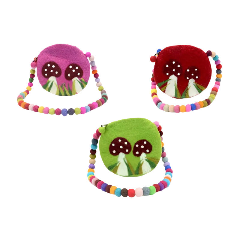 Three small felt mushroom-shaped shoulder bags in pink, red, and green, each with a colorful beaded strap and embroidered brown mushrooms with white spots on the front, shown on a plain white background.