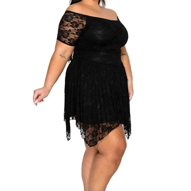 A woman modeling a black off-the-shoulder lace mini dress with a pleated skirt and black strappy high-heeled sandals against a plain white studio background.