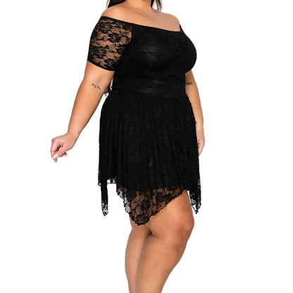 A woman modeling a black off-the-shoulder lace mini dress with a pleated skirt and black strappy high-heeled sandals against a plain white studio background.