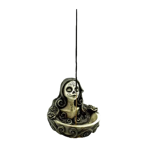 Decorative incense holder shaped like a skull with intricate designs on a white background