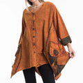 Woman wearing an orange poncho tunic with brown accents on a white background