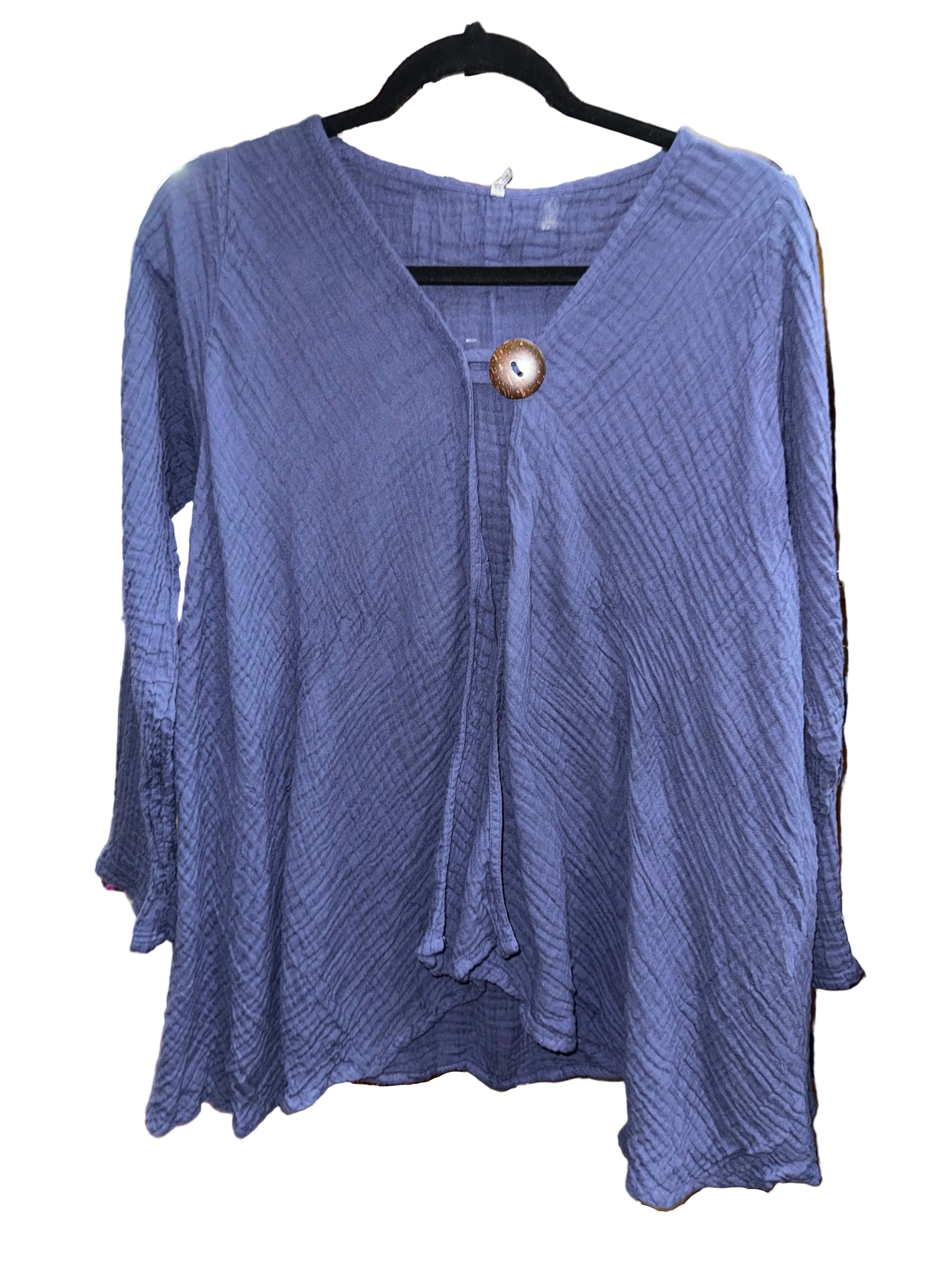 A textured lavender-purple long-sleeve blouse with a V-neckline, front tie detail, and a decorative wooden button, hanging on a black hanger on a white background.