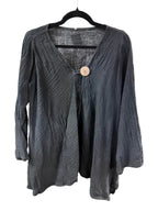 A black textured long-sleeve top with a V-neck and a single wooden button closure, hanging on a black hanger on a white background.
